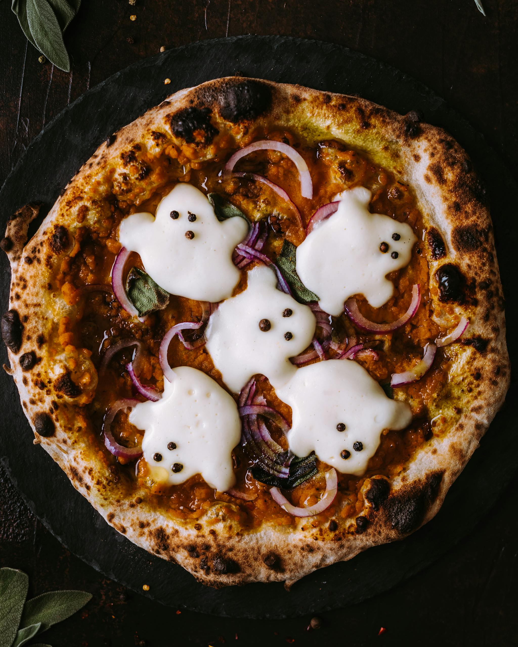 A spooky pizza decorated with ghost-shaped mozzarella, perfect for Halloween celebrations.