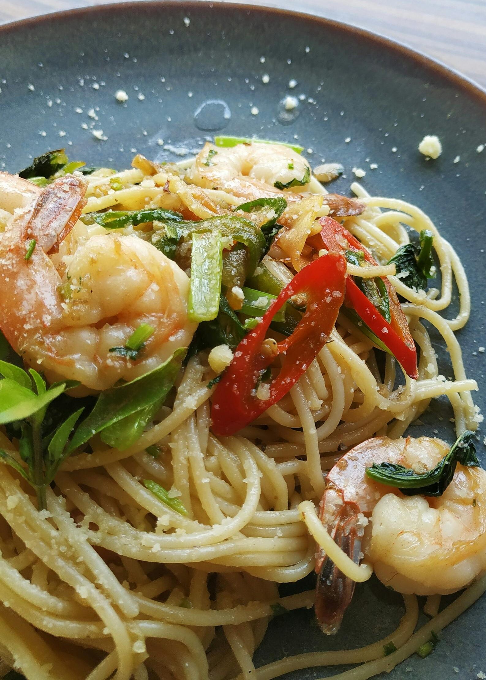 Appetizing shrimp pasta garnished with fresh chili and herbs in a close-up view.