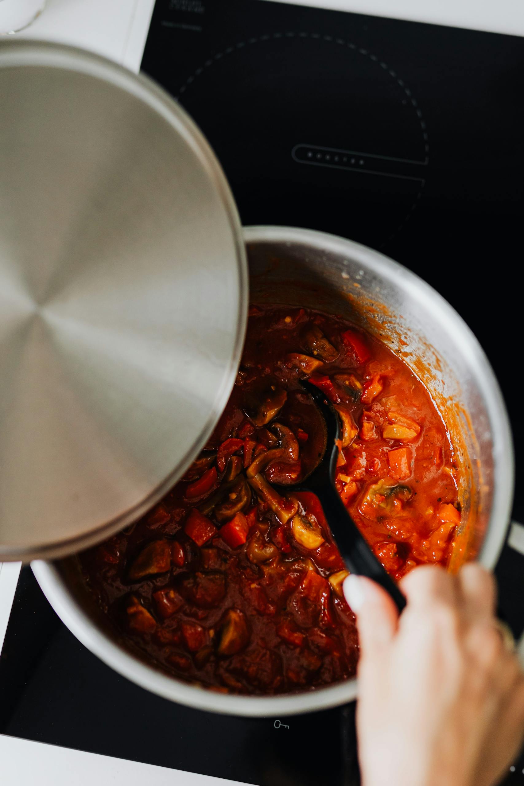 Close-up of shakshuka cooking in pot with spoon stirring. Perfect for culinary enthusiasts.