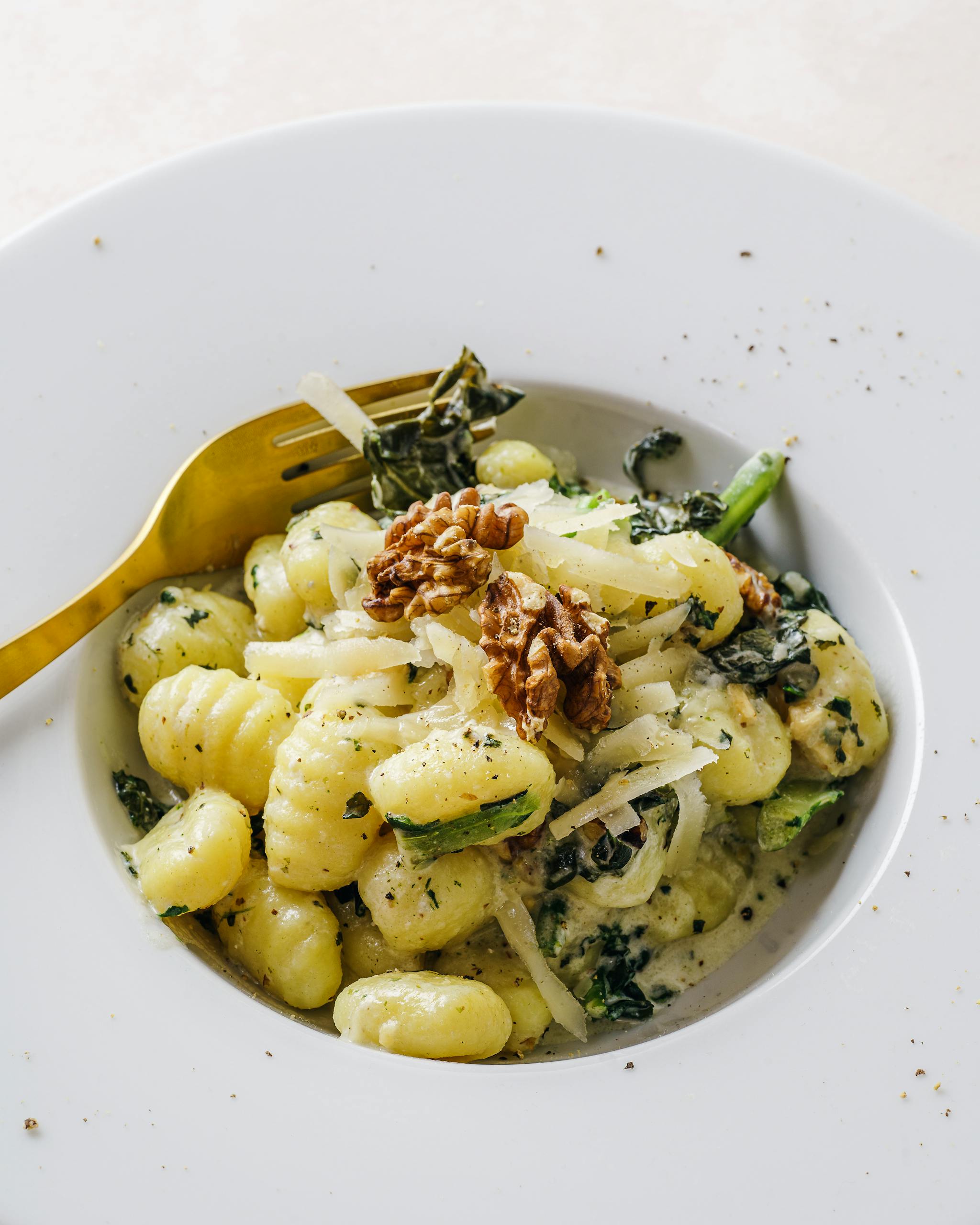 Elegant plate of gnocchi pasta topped with kale and walnuts, perfect for a gourmet meal.