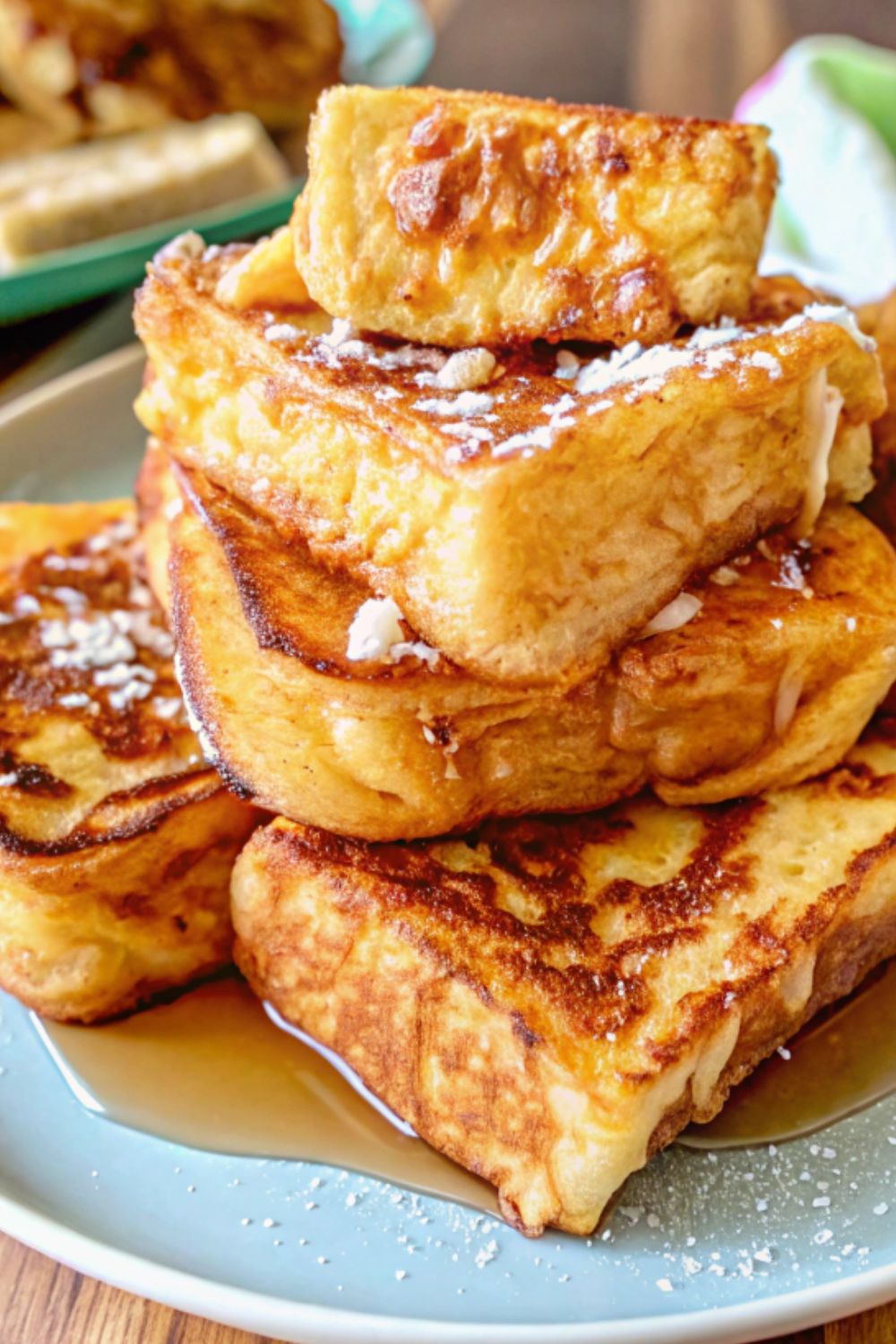 A plate of french toast with syrup and icing sugar.