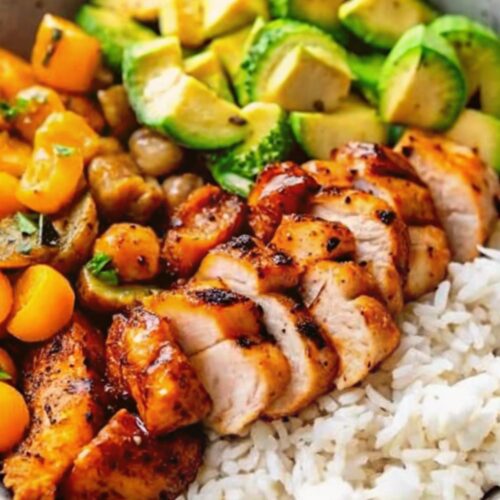 Sliced cooked chicken in a bowl with rice and vegetables.