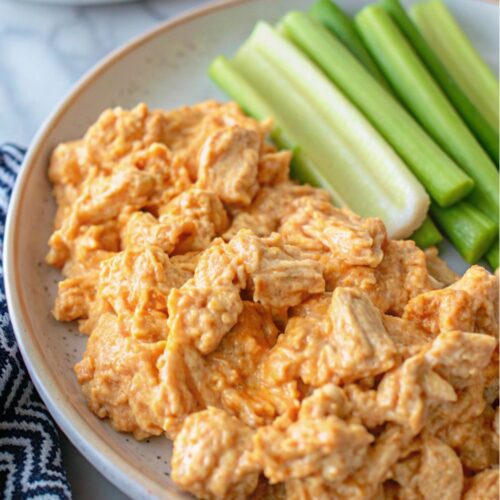 Chicken salad on a plate with celery sticks.