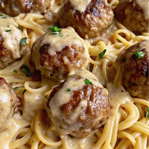 Meatballs served on pasta with sauce.