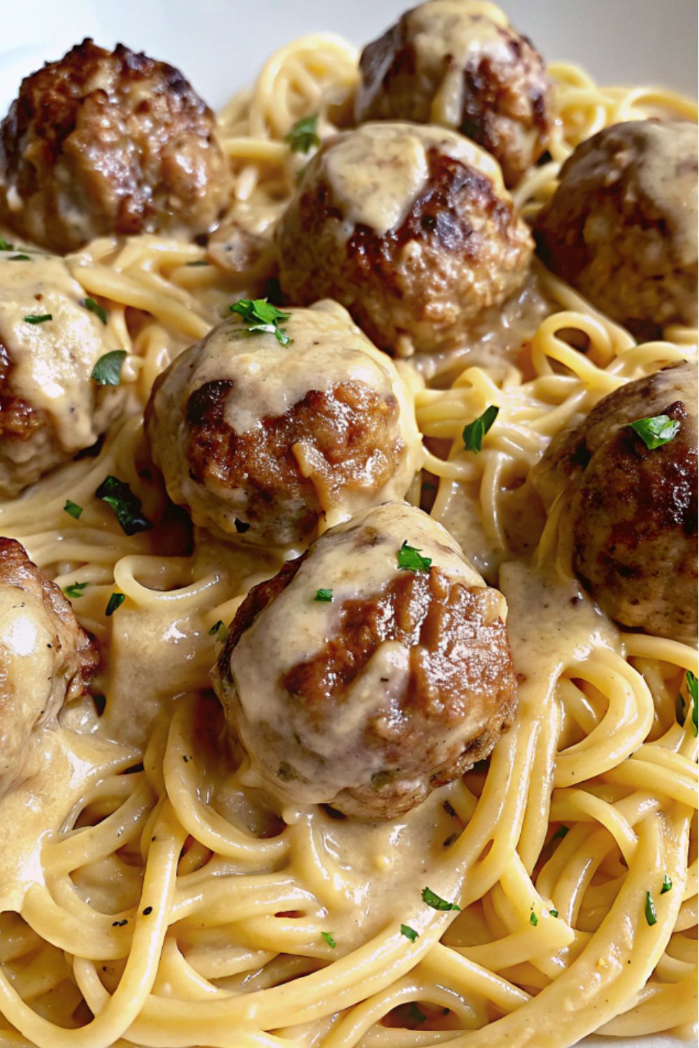 Meatballs served on pasta with sauce.