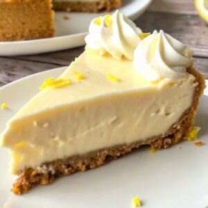 Slice of lemon pie with whipped cream on top and lemon zest garnish.